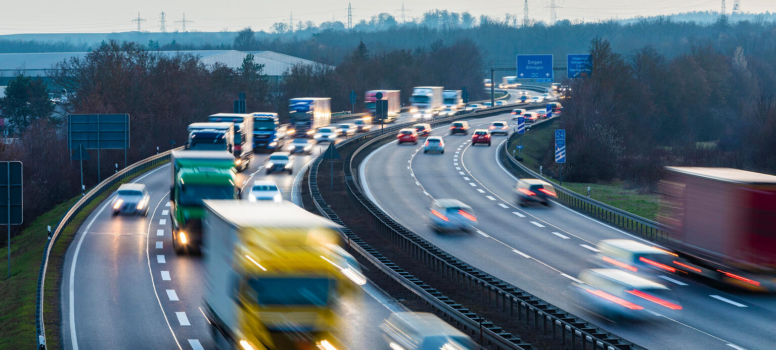 Eine Autobahn in Deutschland auf der Autos und LKWs fahren. Dien Ansicht ist verschwommen.