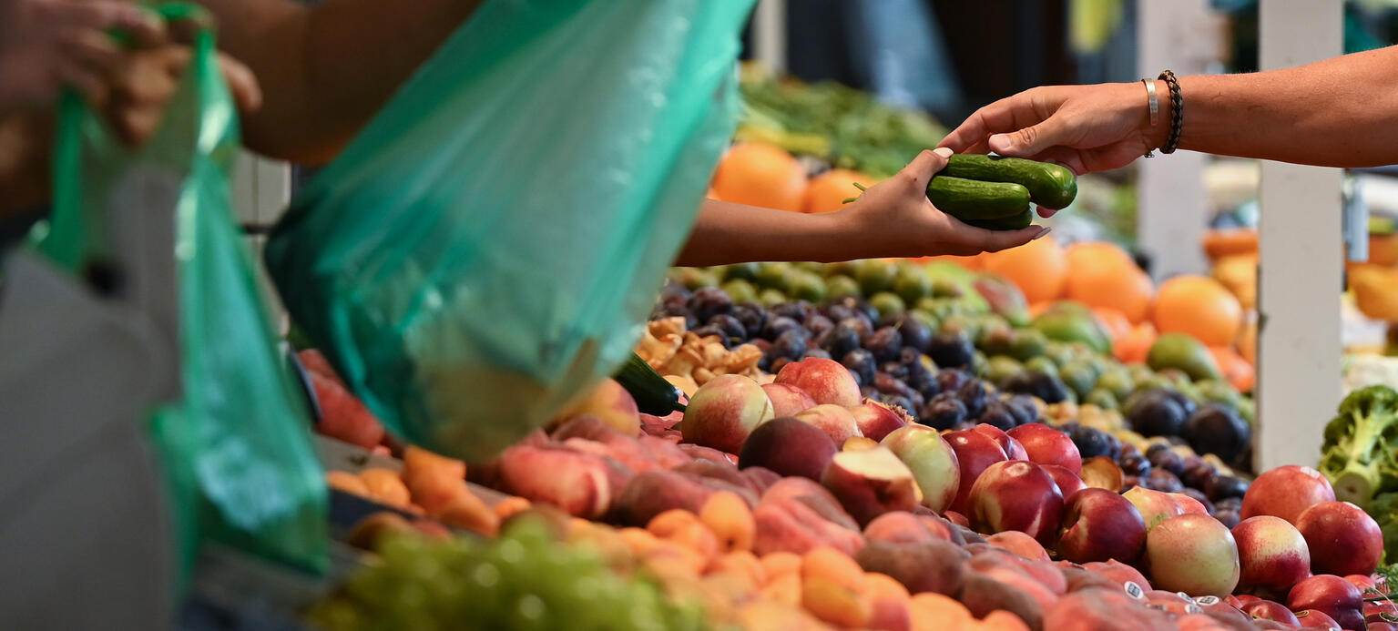 Marktbesucher werden auf dem Wochenmarkt an einem Obst- und Gemüsestand bedient. 