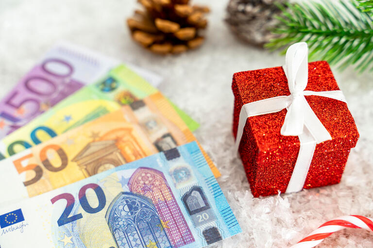 Euro Bargeld Scheine in Schnee zwischen winterlicher Dekoration und Geschenken