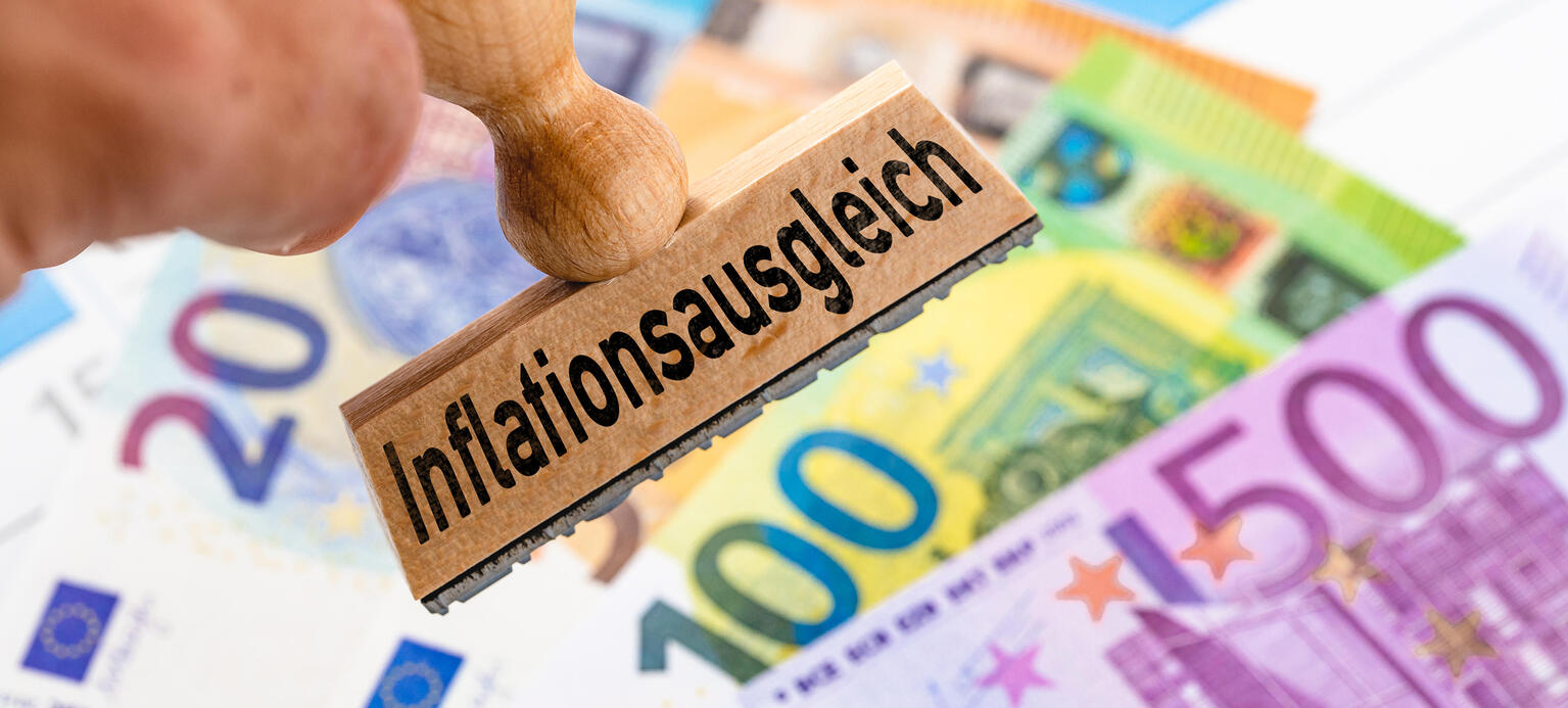 Inflationsausgleich, steht auf einem Stempel neben Euro Geldscheinen.