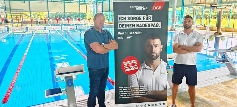 Schwimmmeister Jens Popke (rechts) mit seinem Betriebsleiter Torben Kablau im Schwimmbad in Flensburg mit Kampagnen-Plakat