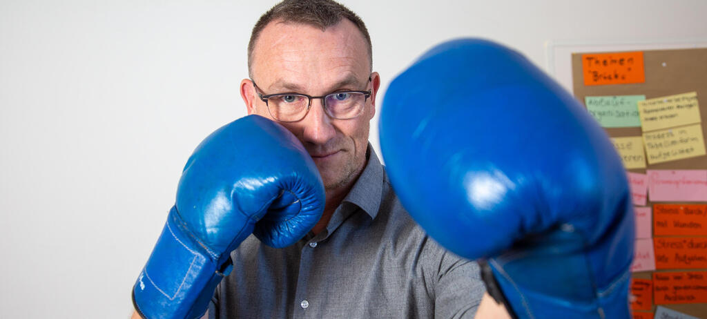 Soziologie-Professor Jonas Grutzpalk mit blauen Boxhandschuhen