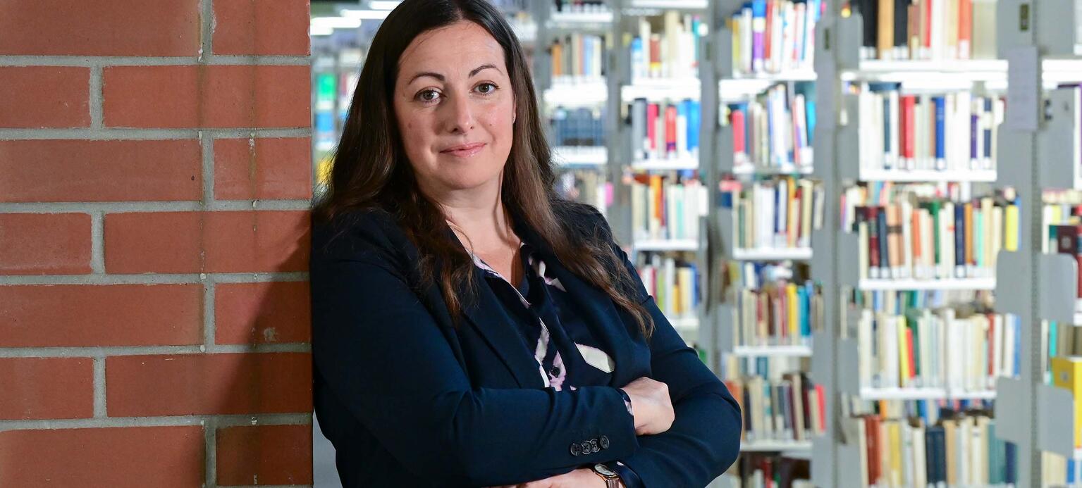 Porträt von Prof. Isabell Hensel, Uni Kassel, vor Bücherregal stehend