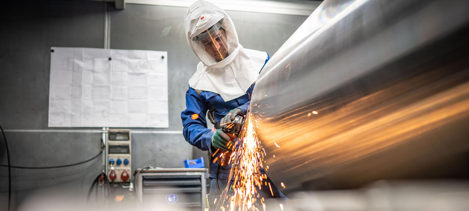 Arbeiter mit Schutzmontur beim Schleifen beim Maschinenbauer SMS Group